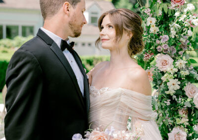Bride looking at her groom with a floral arch around them