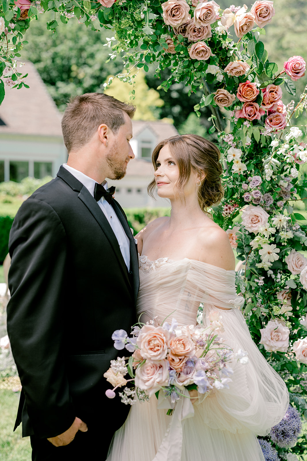 Bride looking at her groom with a floral arch around them